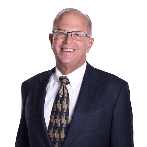A smiling middle-aged man in glasses, a white shirt, a patterned tie, and a dark suit against a white background.