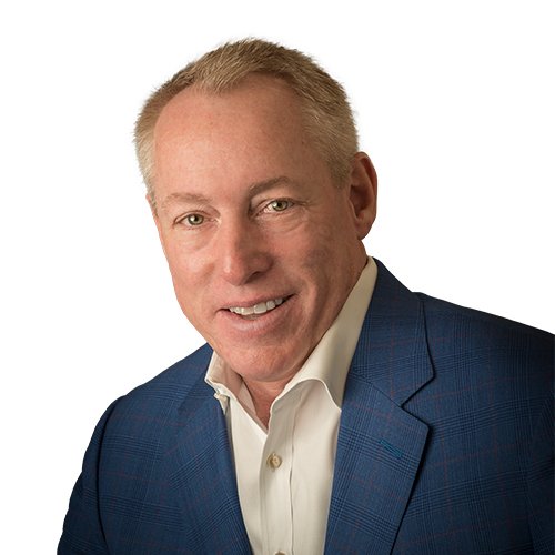 A smiling man with blonde hair wearing a blue suit jacket and white shirt against a white background.